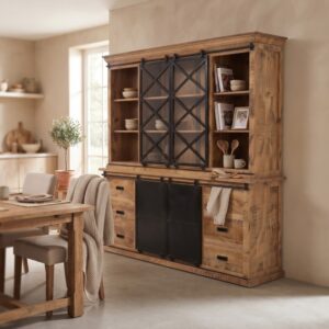 Een schuine hoekopname van de buffetkast mangohout 200cm in een stijlvolle eetkamer, met op de voorgrond een houten eettafel en stoelen met een plaid. De planken van de kast zijn gevuld met servies en kookboeken, wat zorgt voor een gezellige en huiselijke sfeer.